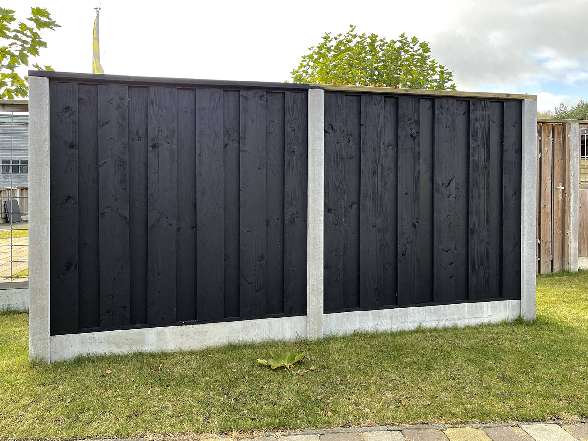 Hout en beton schutting met zwart vuren.