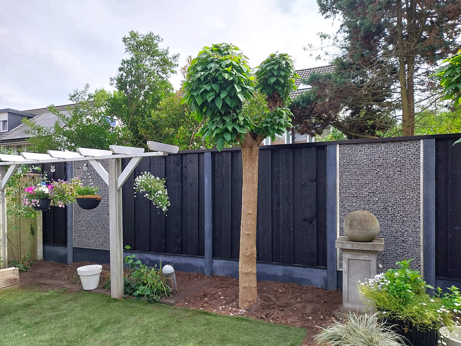 antraciet beton schutting met zwart geschilderde schotten en breuksteen